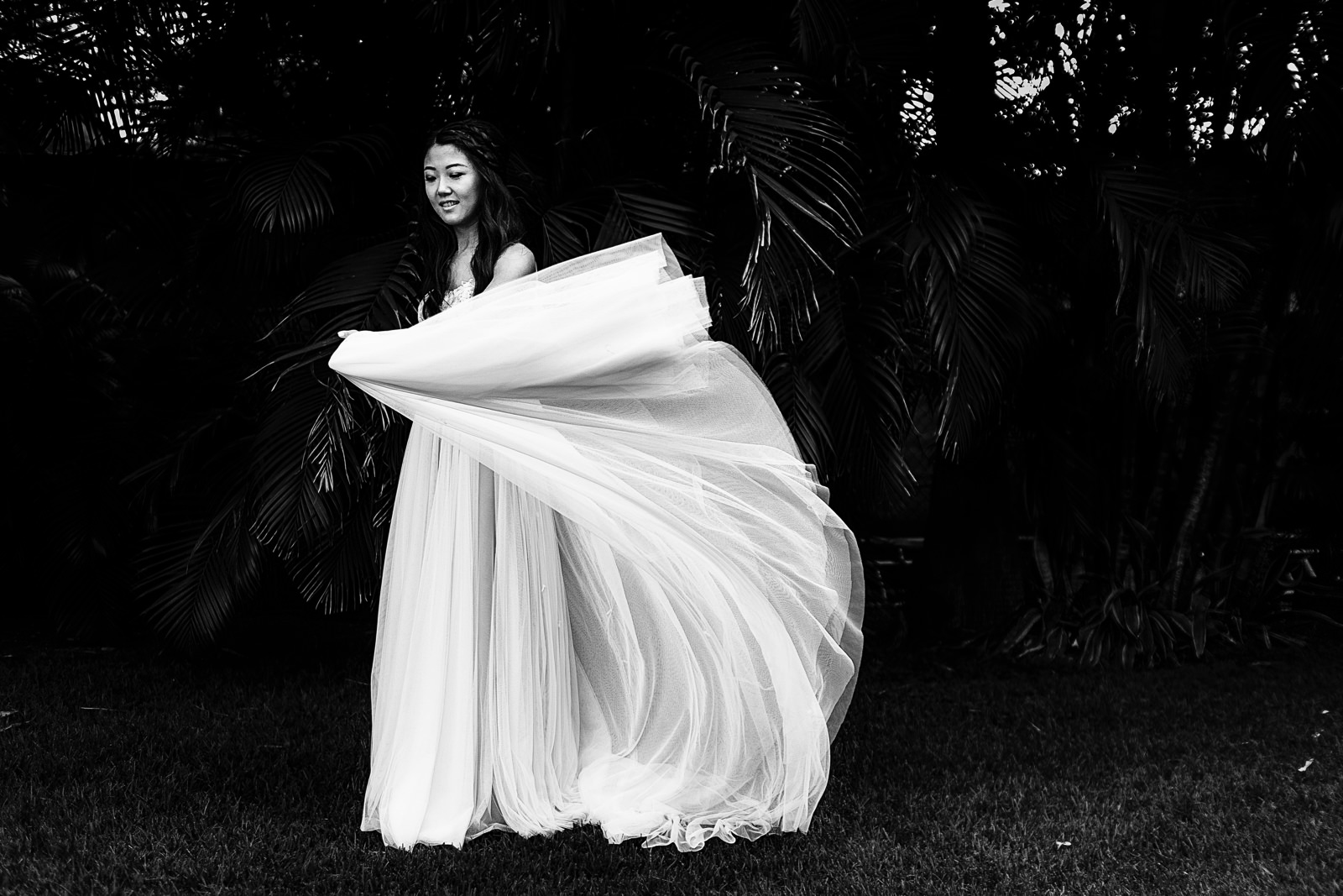 Bride plays with her dress in front of the palm trees at the garden of Martoca.