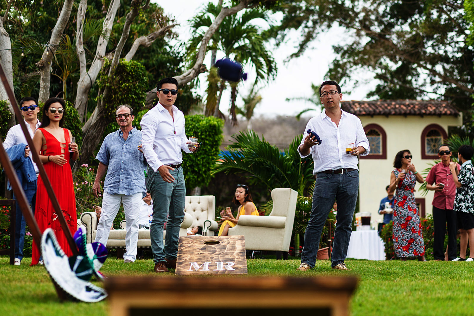 Wedding guests playing with sandbags while the ceremony takes place.