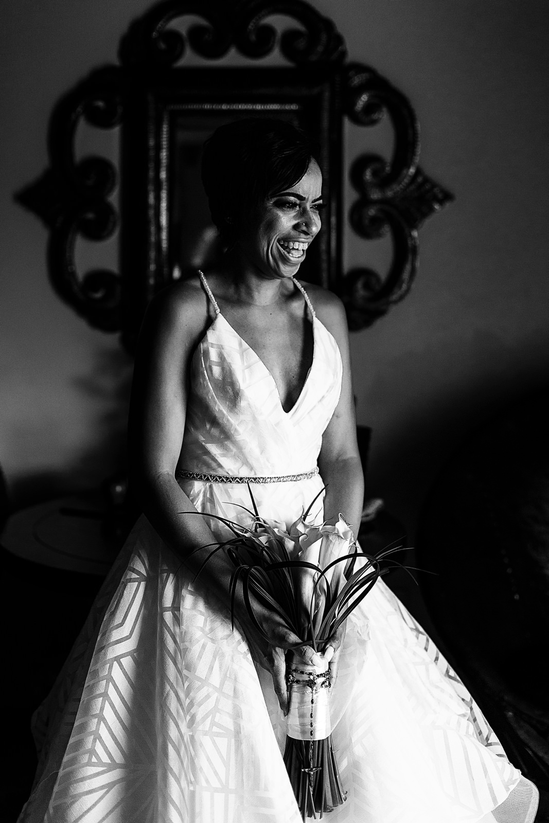 Bride standing near a window for a portrait while laughing