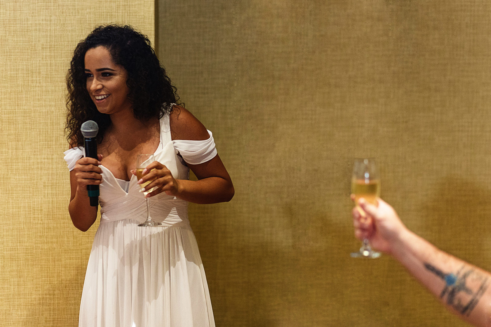 Young woman giving a speech and holding a glass of champagne
