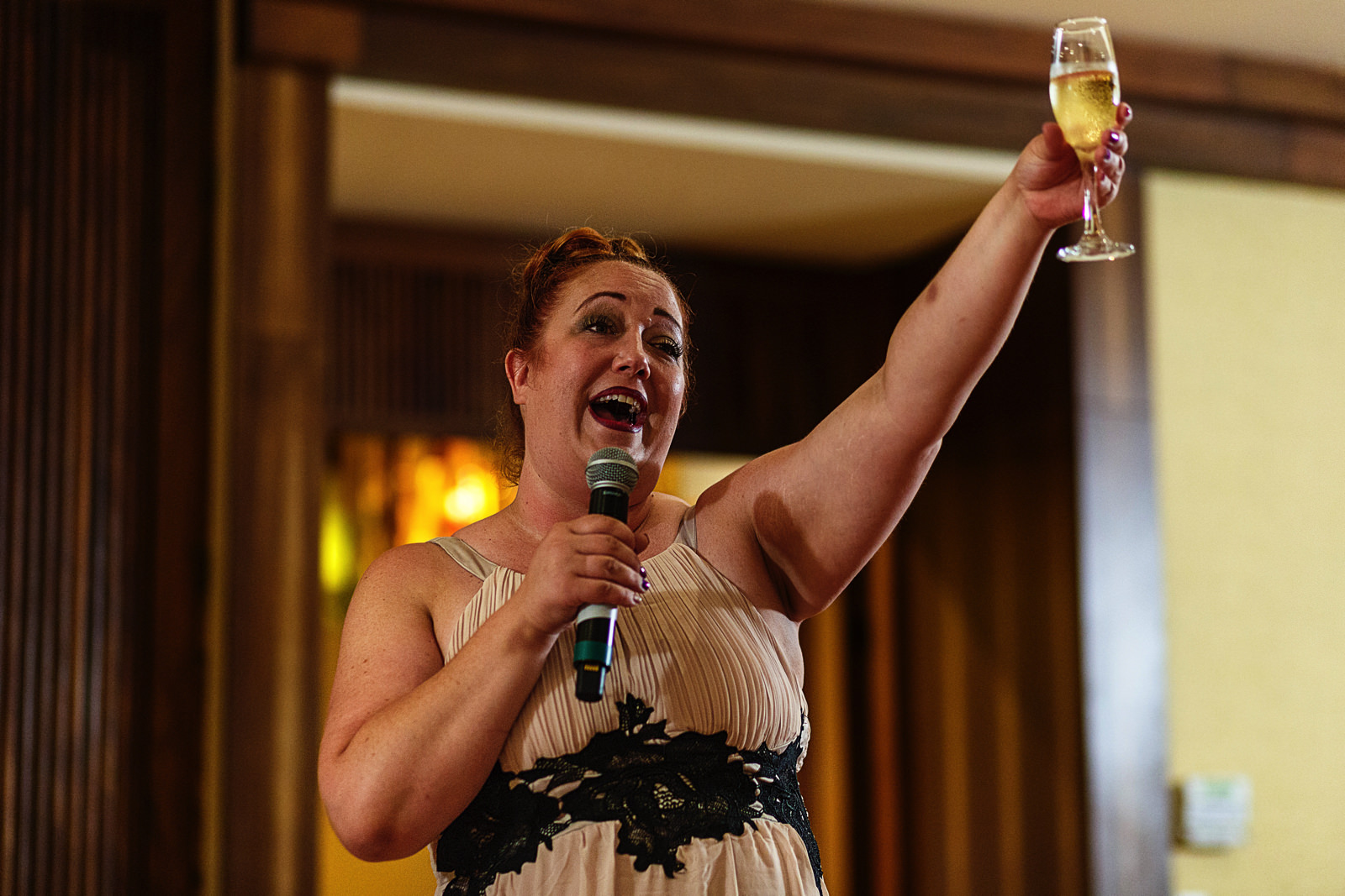 Wedding guest raise her champagne glass at the end of her speech