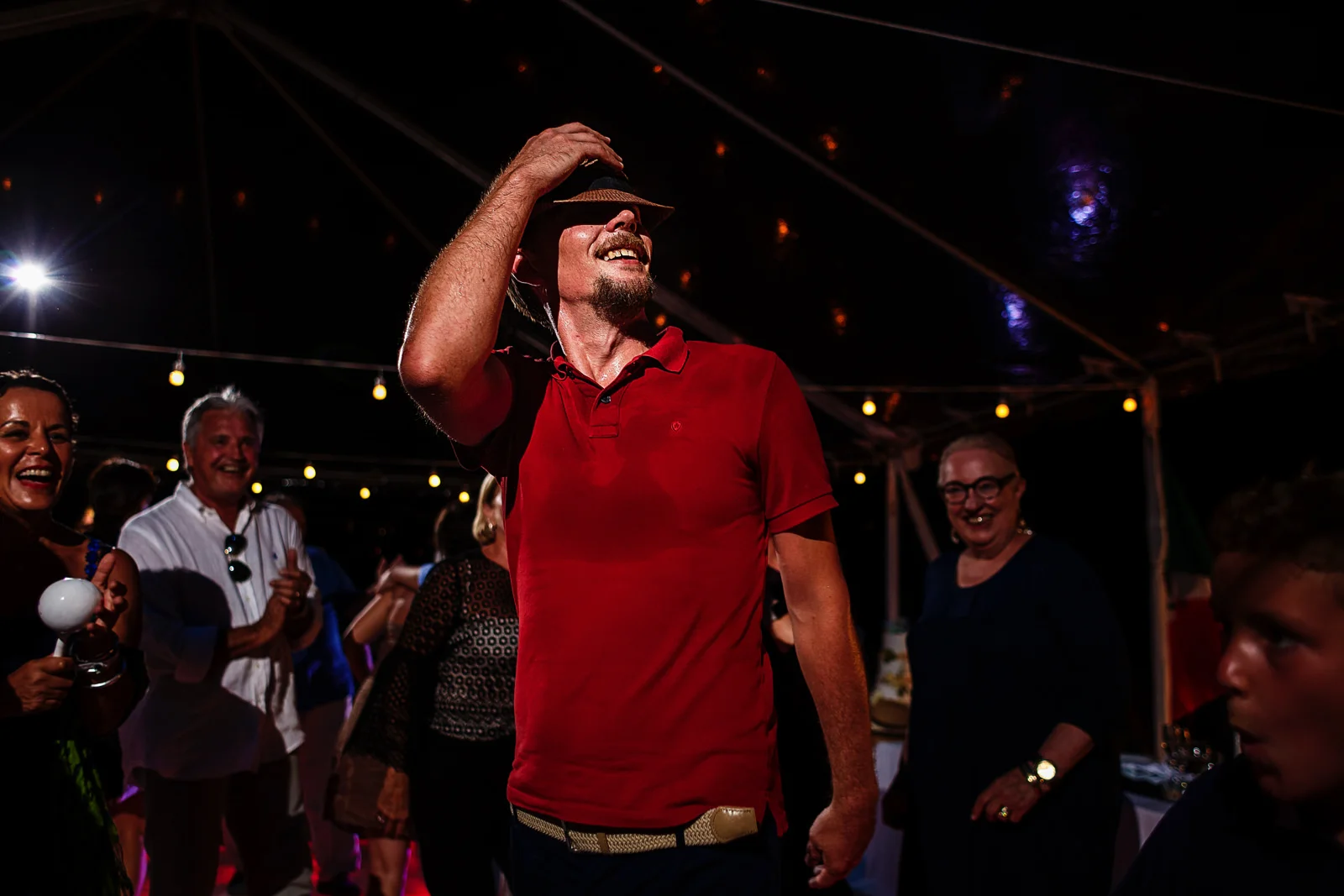 Wedding guest showing his best dance moves dressing a red shirt and a hat