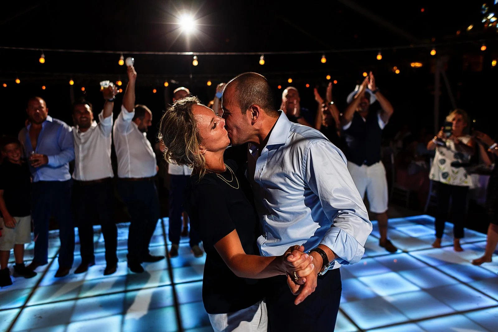 Bride and groom kissing and dancing in front of their wedding guests in the middle of the dance floor