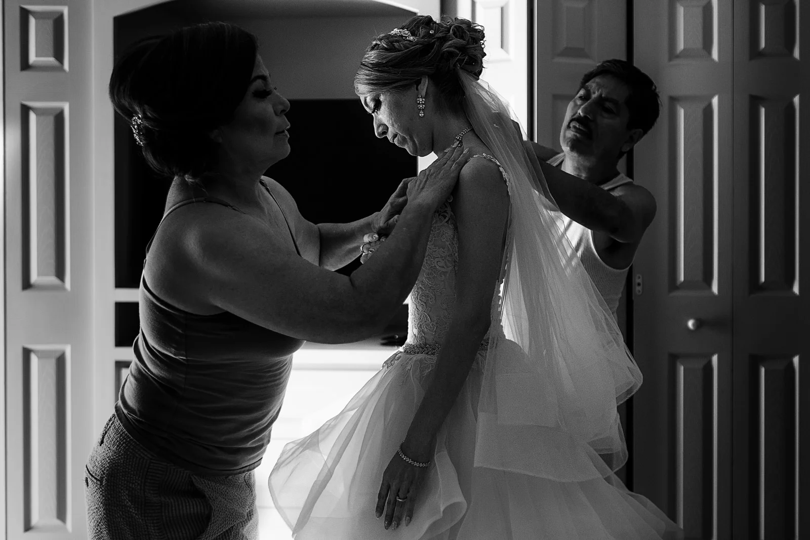 Mom and dad helping their daughter bride to get dress