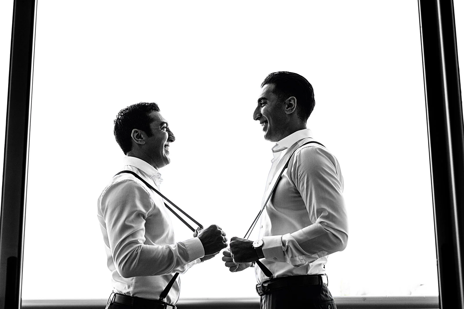 Groom and bestman holding the suspenders for a portrait