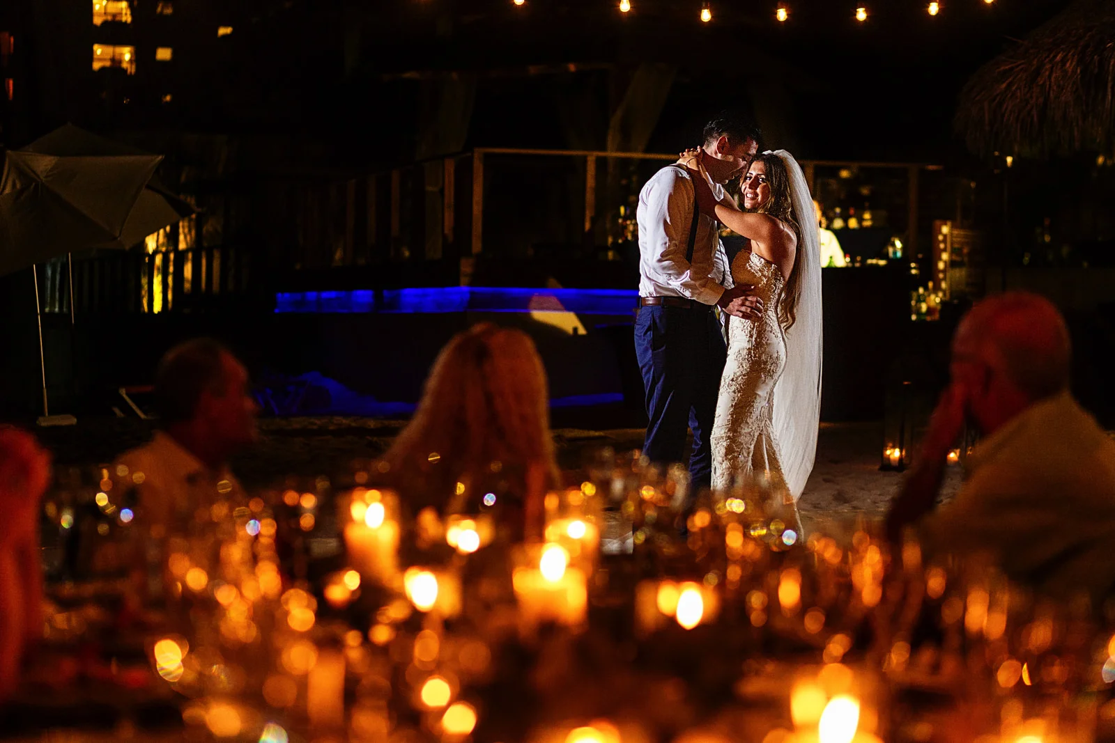 Bride and groom first dance through candles on the table
