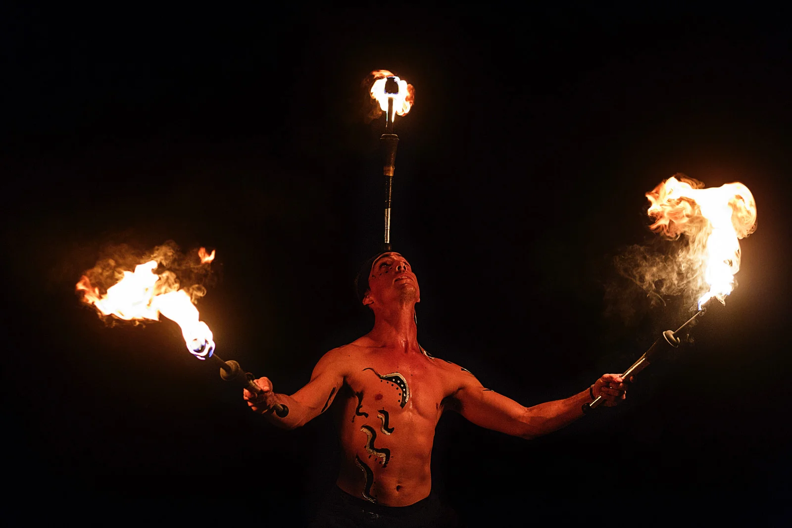 Fire dancer holding a fire stick on his forehead