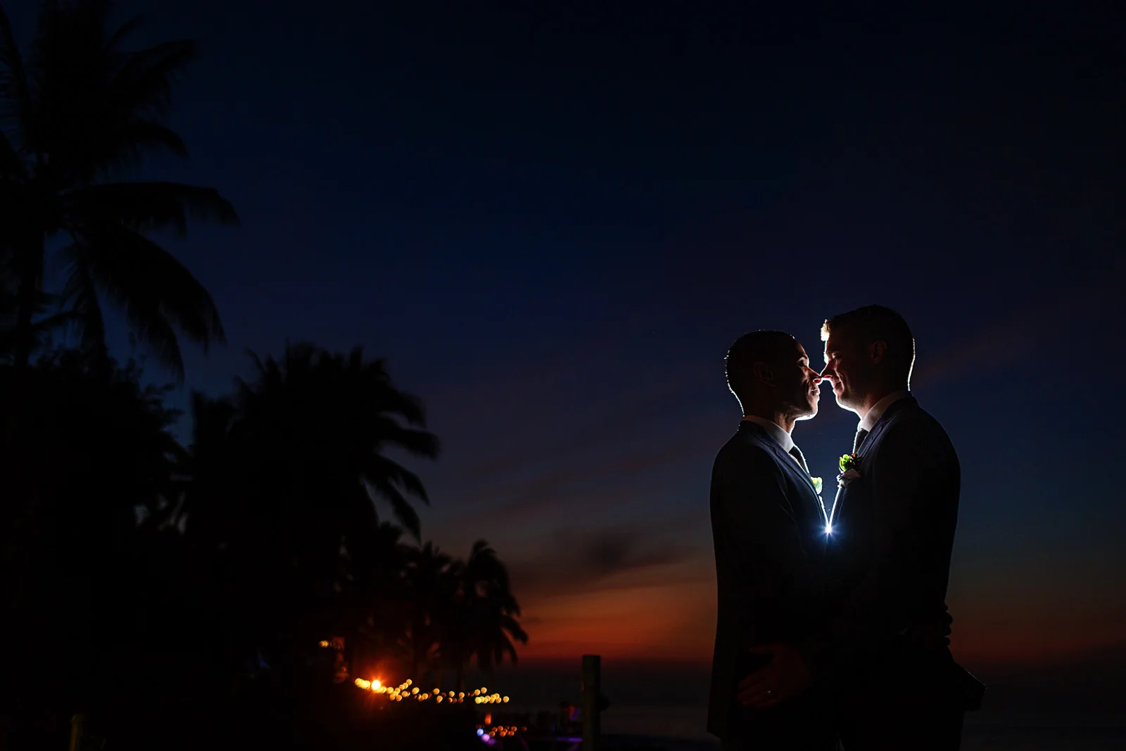 Grooms kissing at sunset after wedding ceremony in Mexico