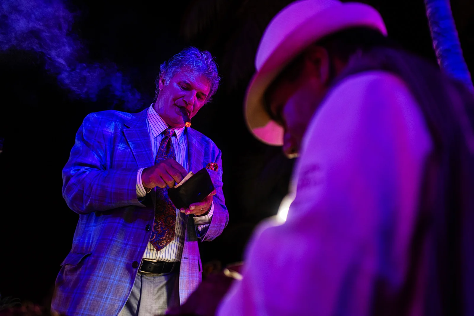 Wedding guest with a cigar in his mouth giving a tip to the cigar maker
