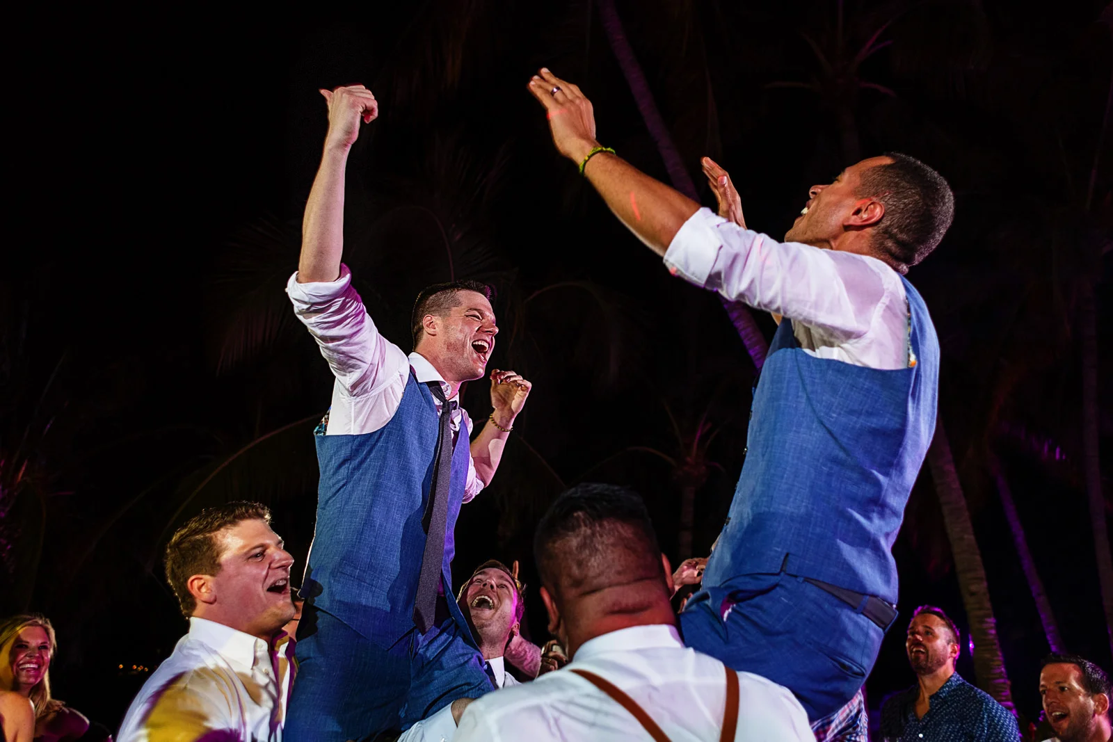 Grooms being raised over the shoulders of their friends and wedding guests