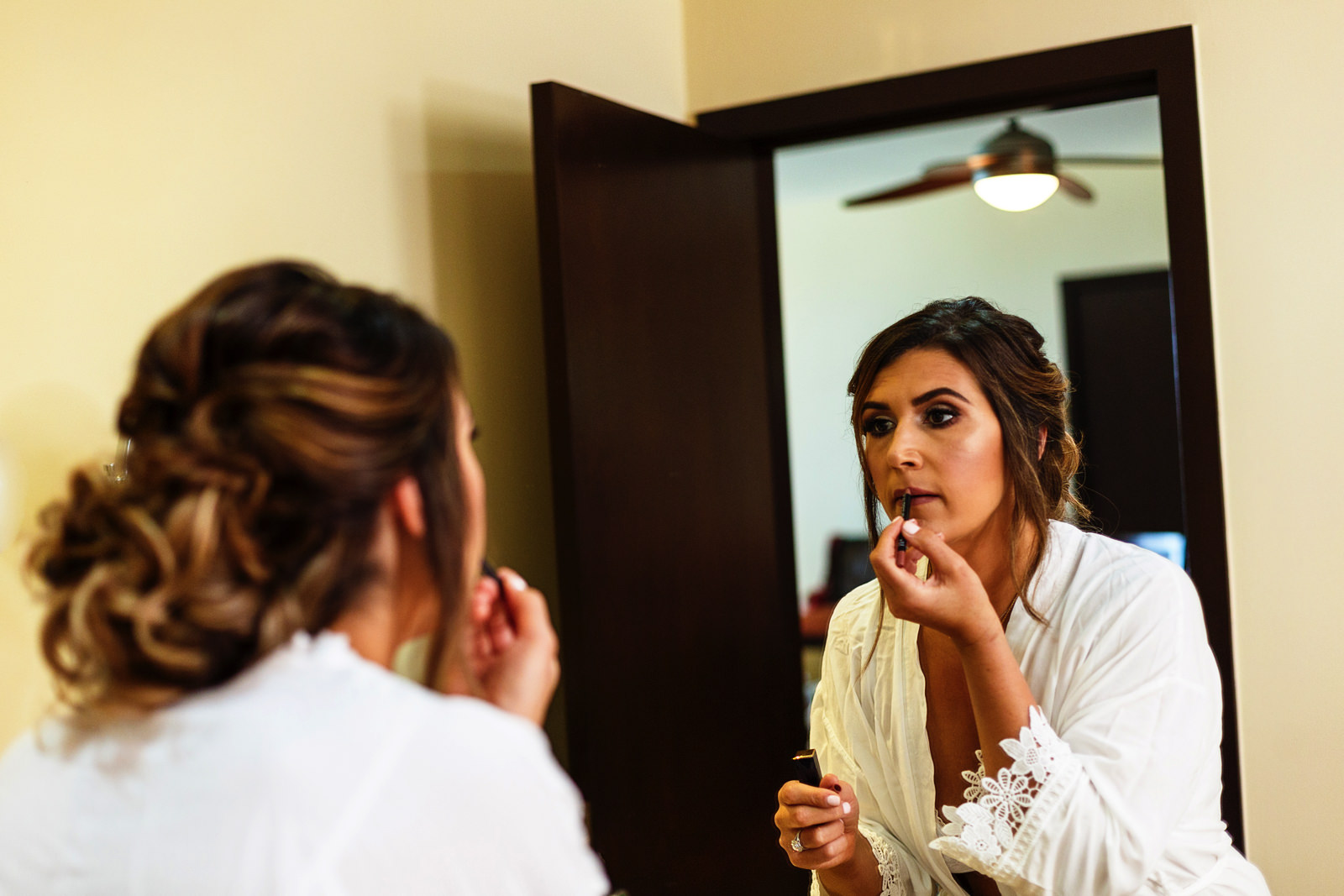 Bride doing her own make-up in front of the mirror of the bathroom