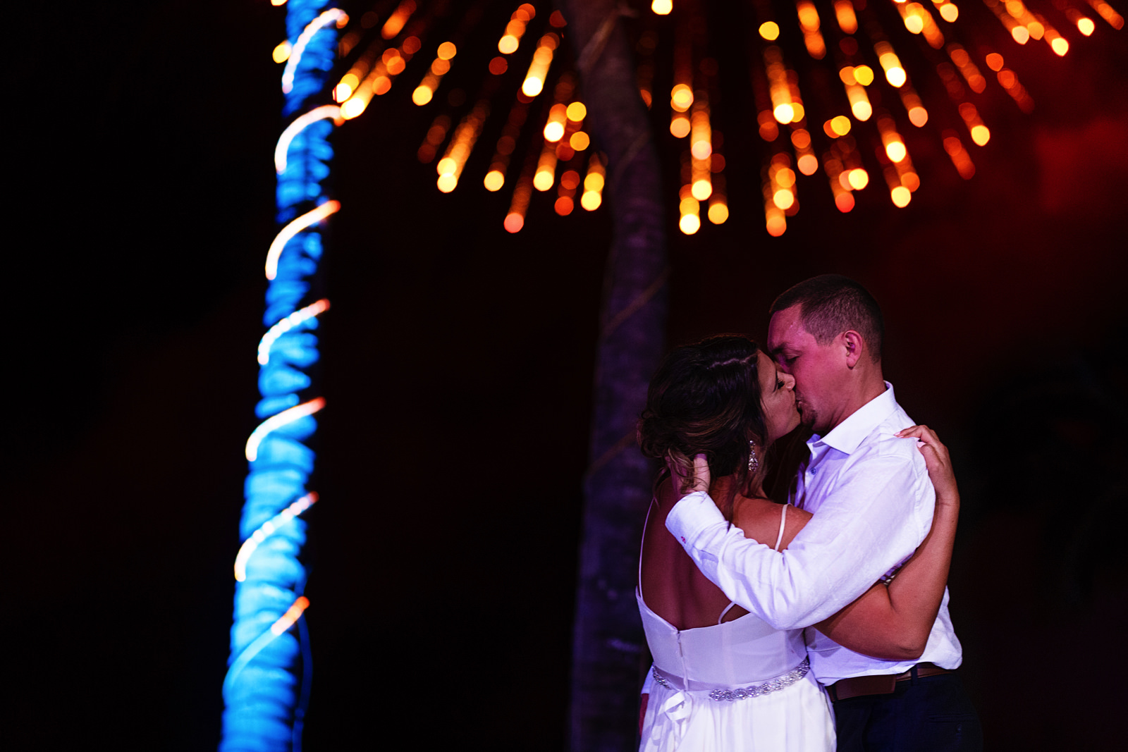 Bride and groom kiss on their first dance under fireworks