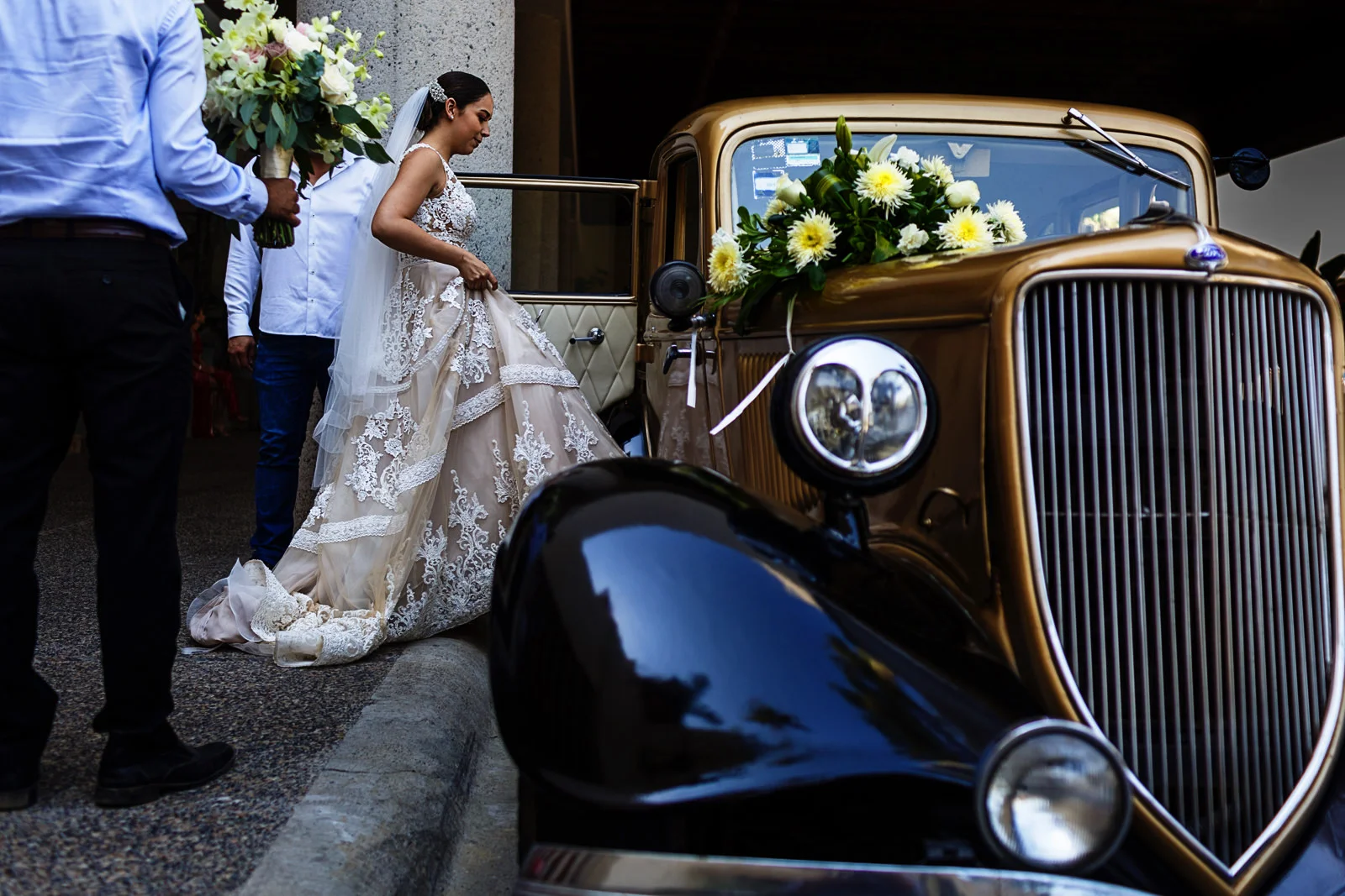 Bride getting into a classic car to go to her catholic wedding ceremony