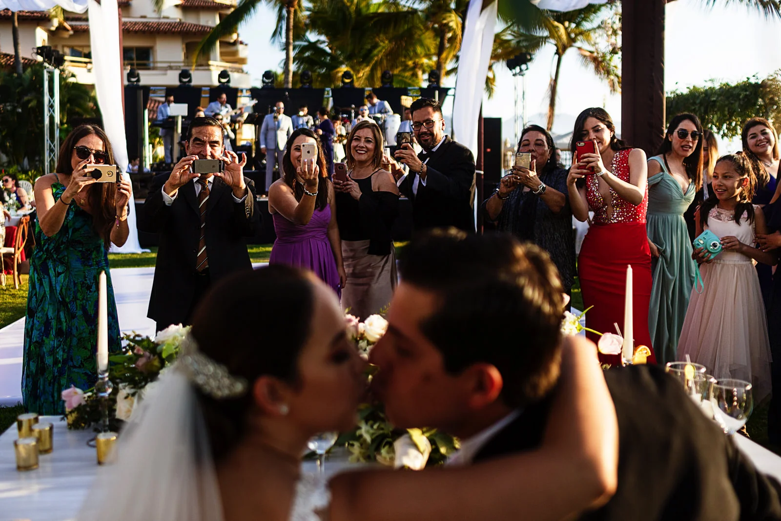 Wedding guests getting a snap photo with their phones of bride and groom about to kiss