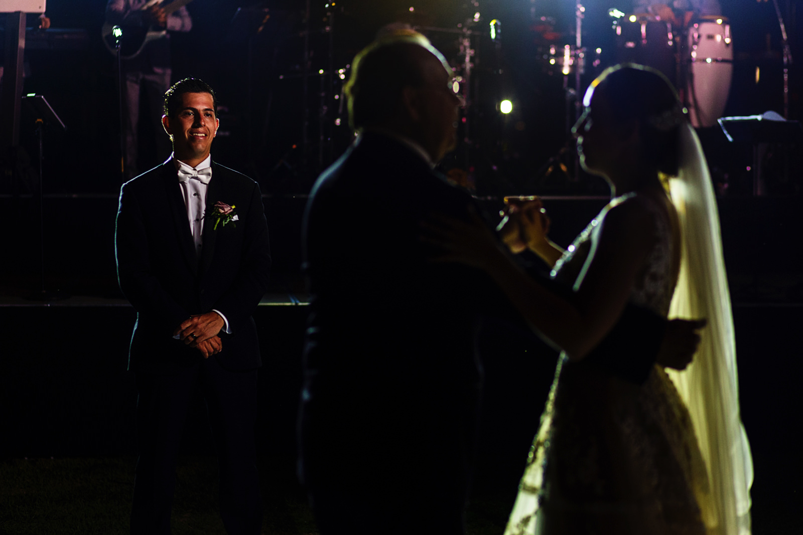 Groom smiling as he sees the father and bride dance