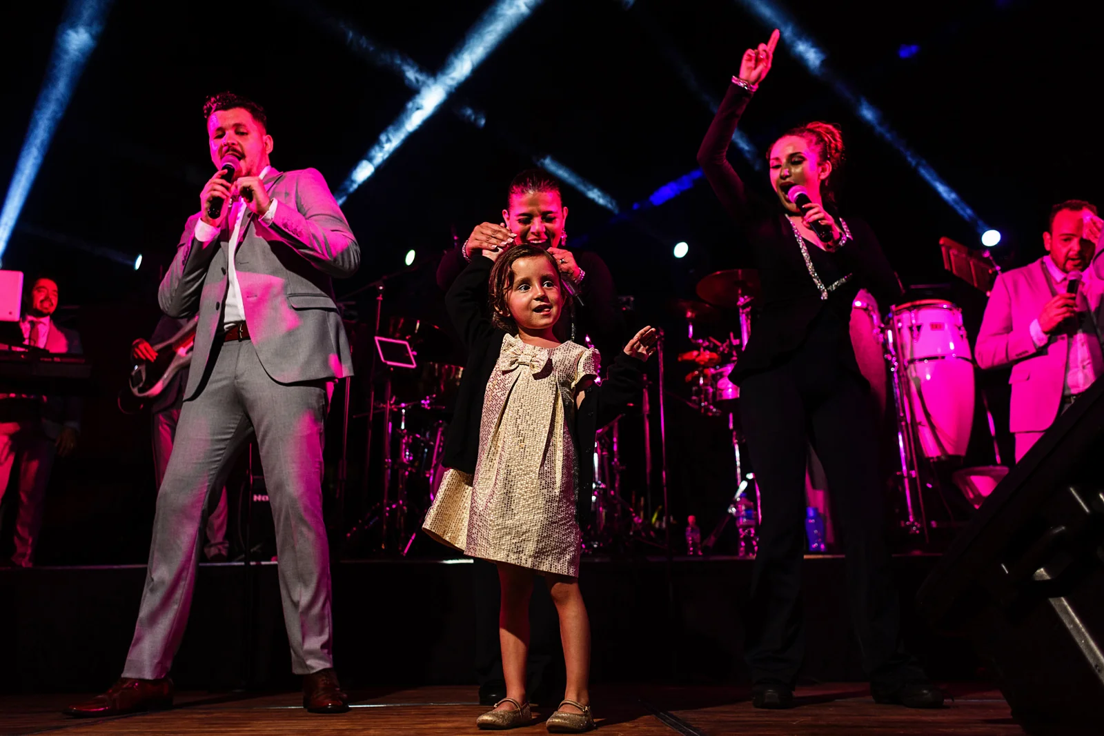Little girl dances on stage with singers of the music band for the wedding