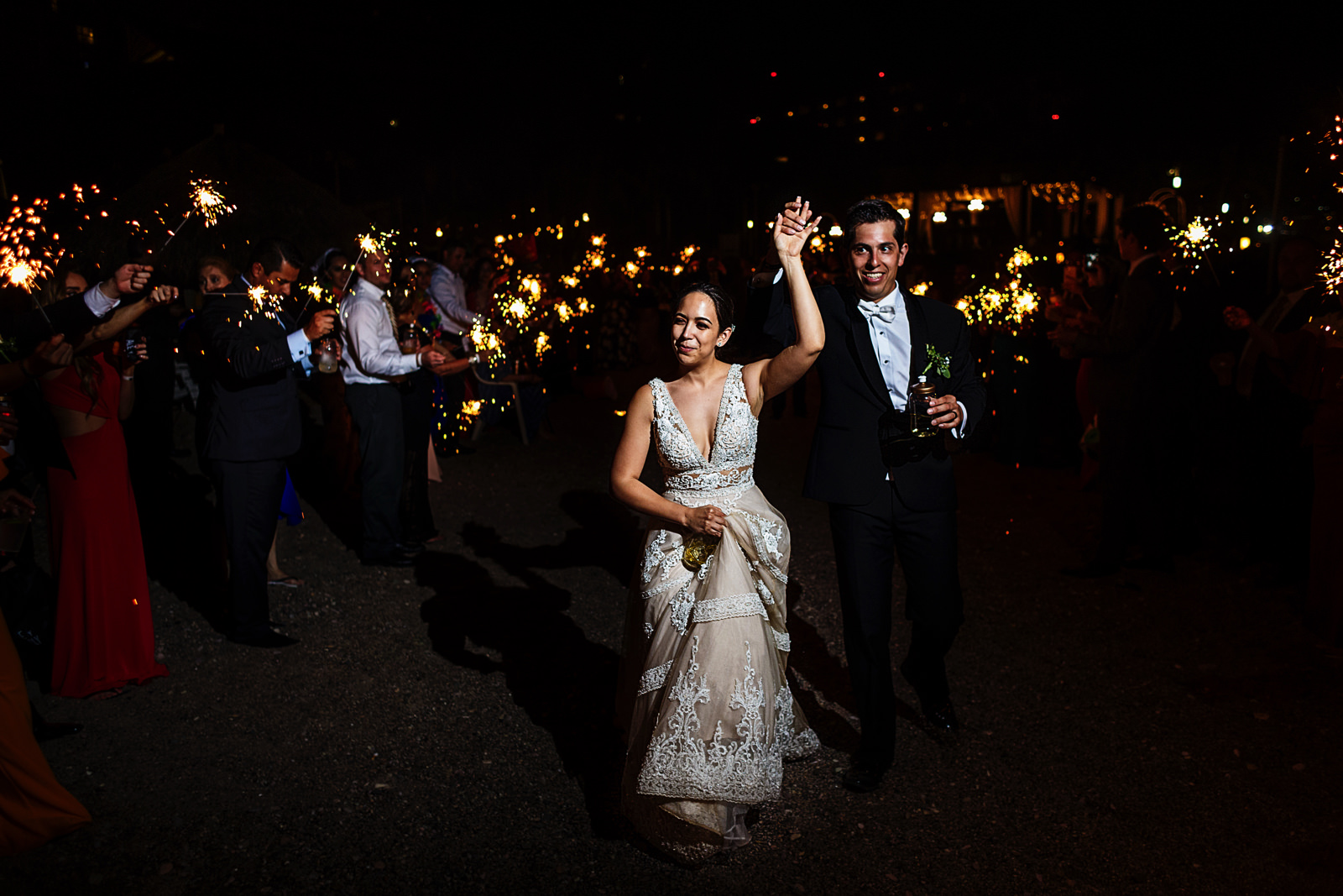 Bride and groom exit the wedding with sparklers on both sides of a friends corridor