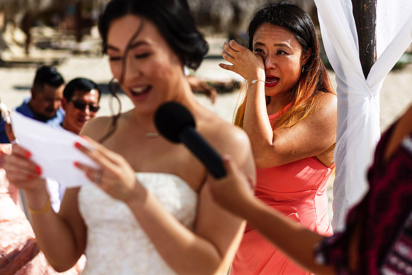 Maid-of-honor cries behind the bride while she is receiving her vows