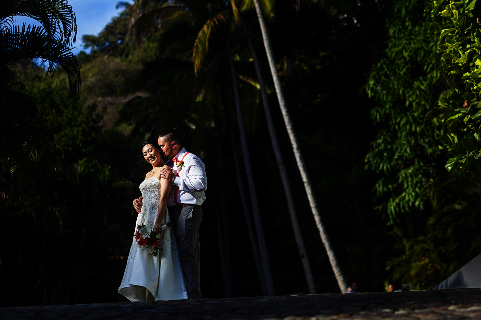 Groom and bride portrait using a spot of direct sunlight surrounded by greenery