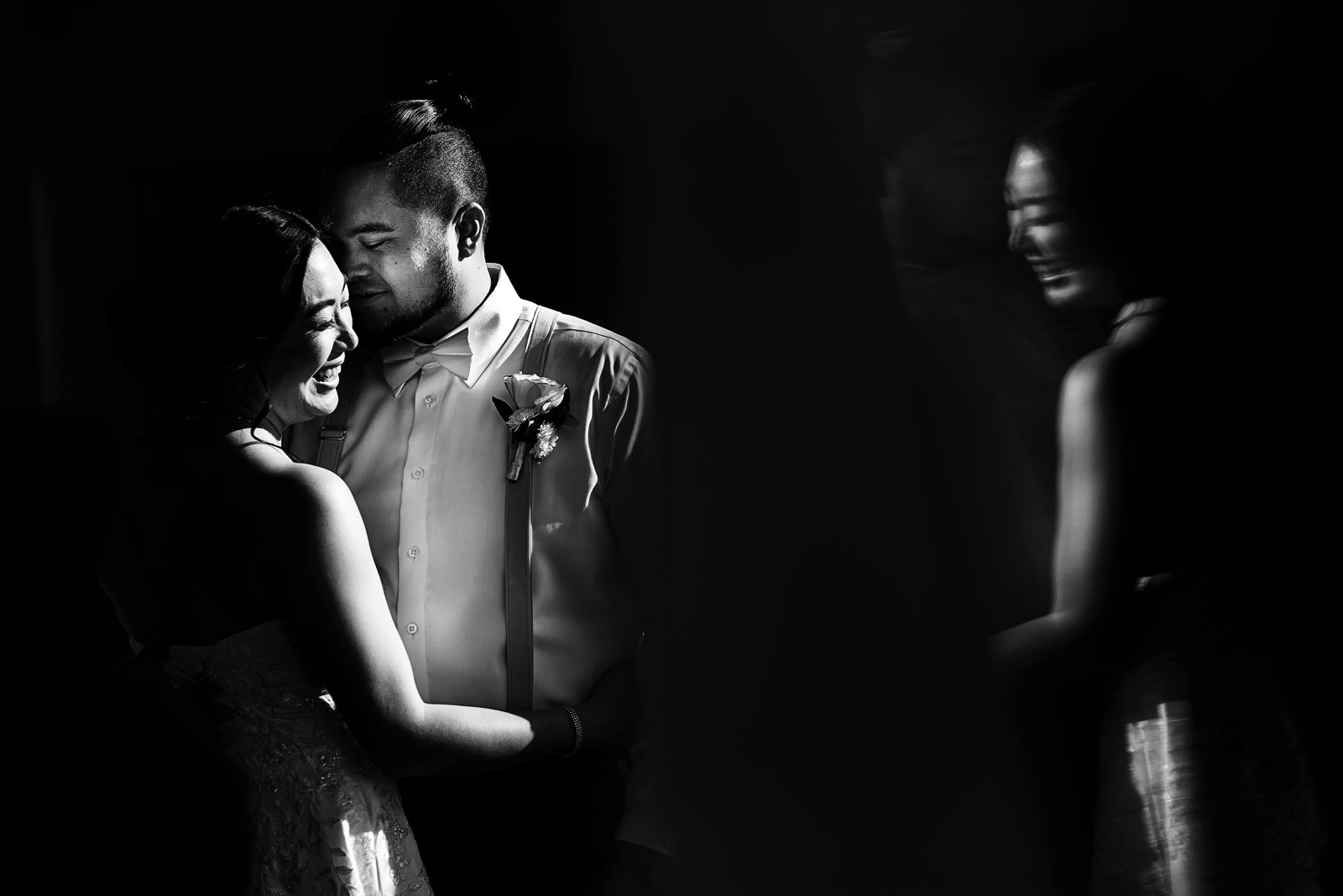 Groom and bride portrait in black and white on a spot of direct sunlight and a reflection of the bride’s laugh