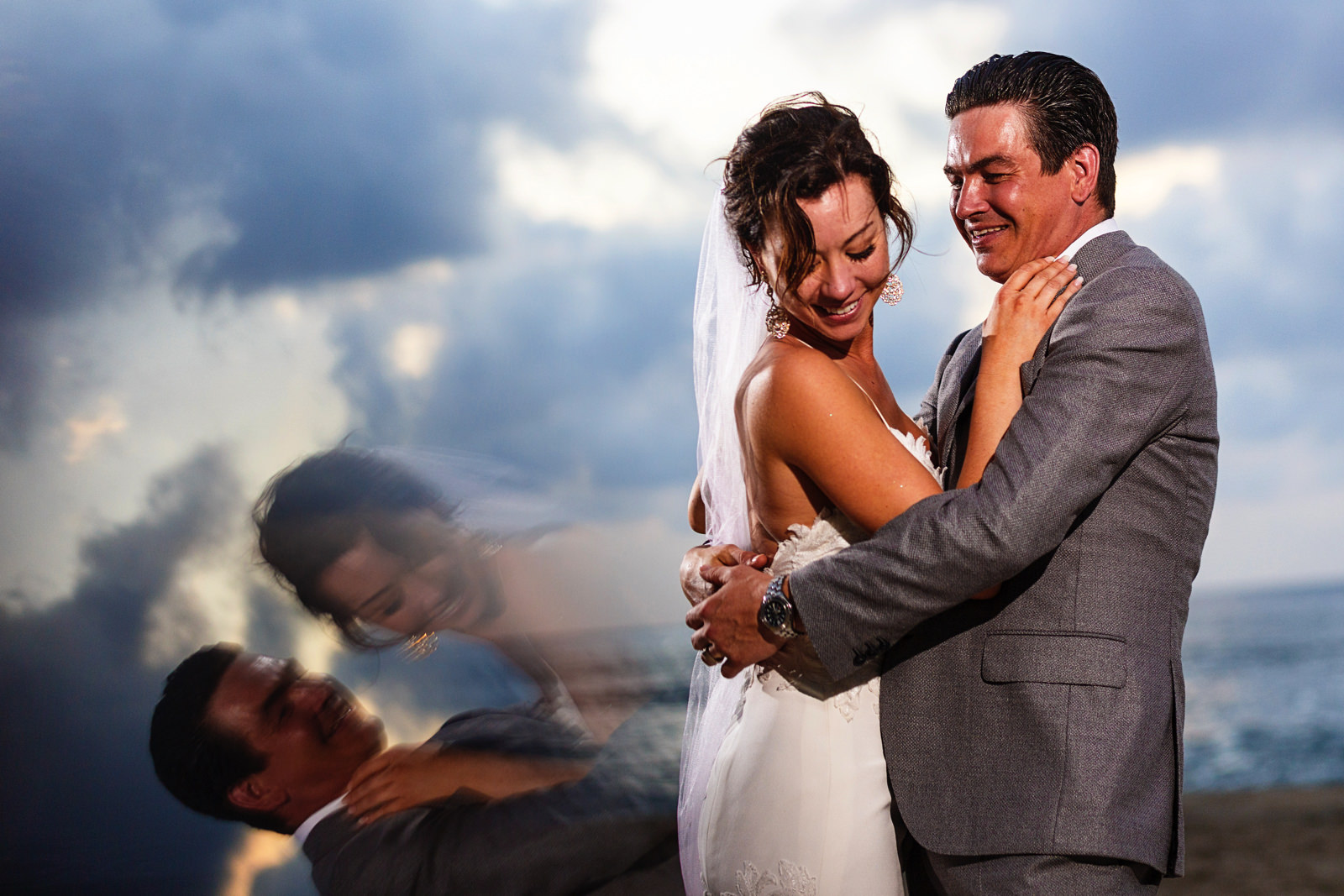 Bride and groom portrait on the beach with the sunset in the background and a prism reflection of the couple
