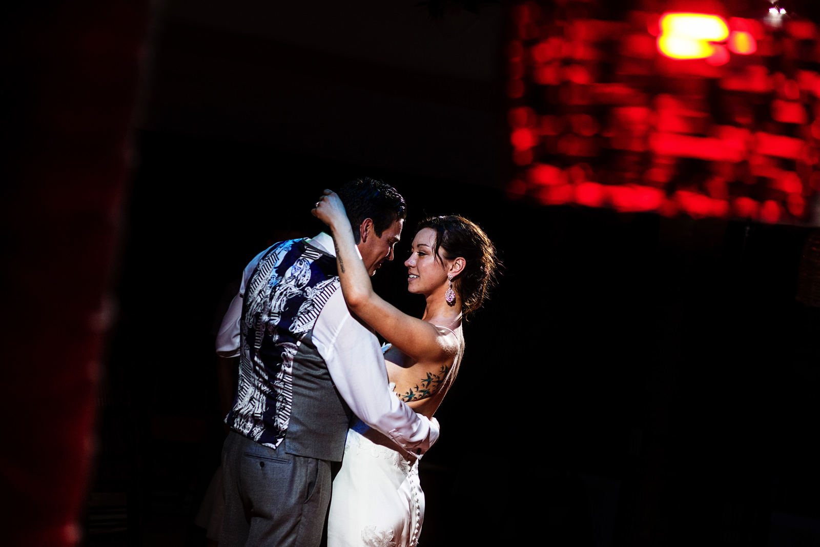 Bride and groom first dance through a column and a red lamp