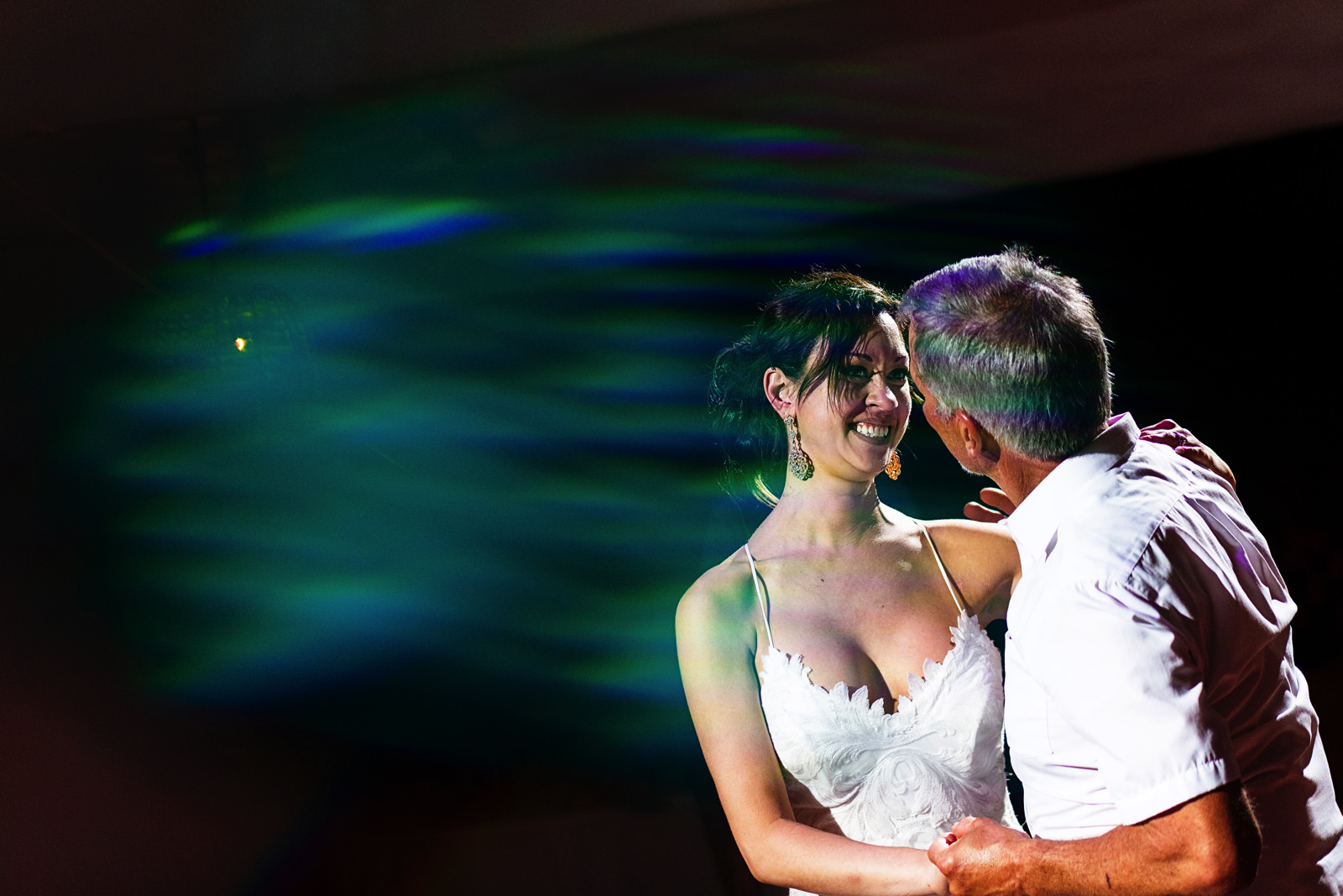 Bride and father dance with a green lens flare
