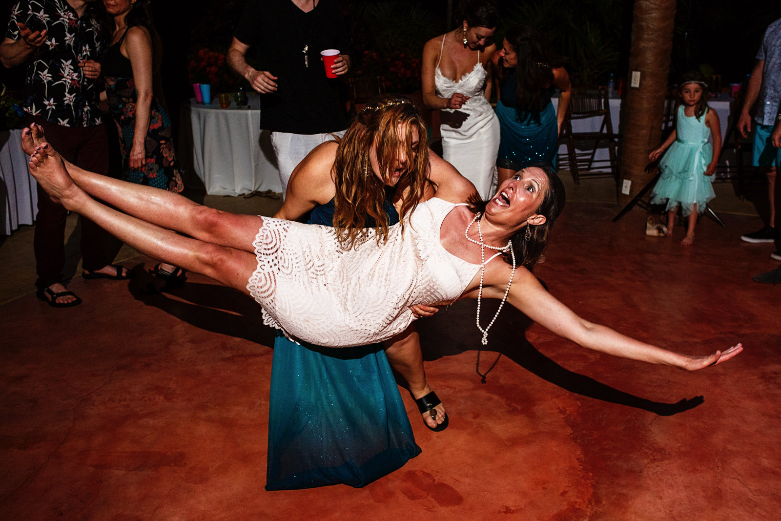 bridesmaid carries a female wedding guest in the dance floor a the party