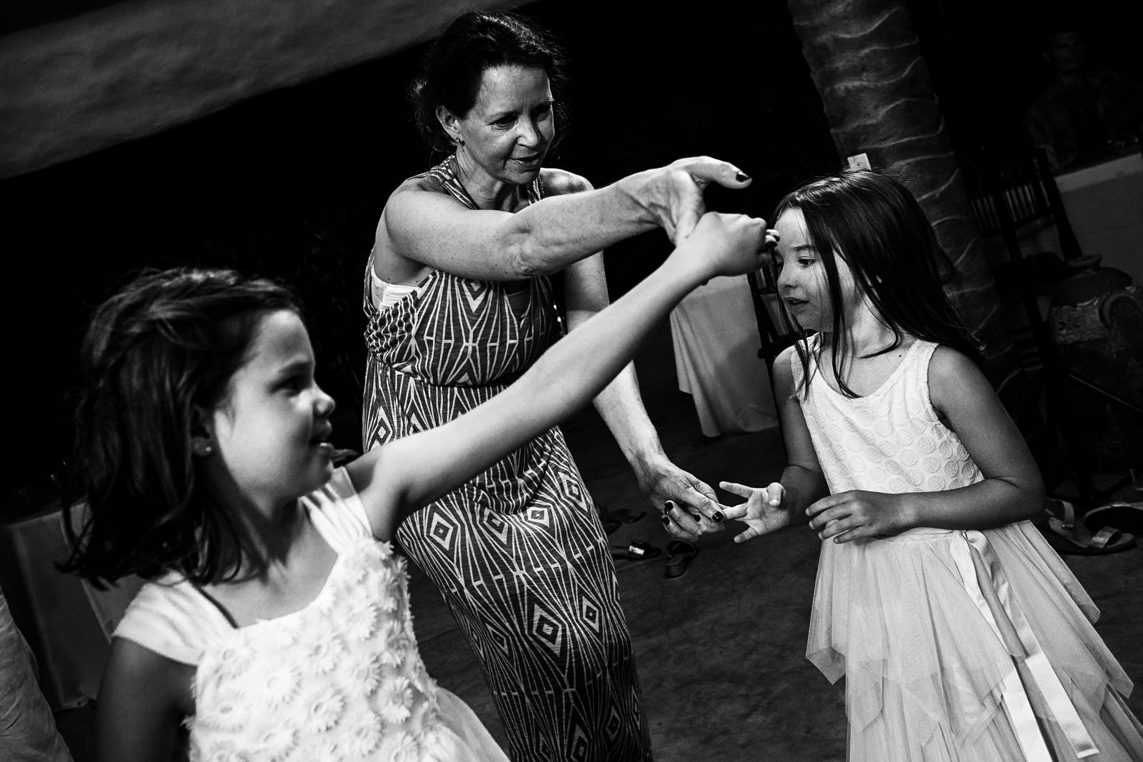 Adult wedding guest dances with two little girls in the dance floor at the party