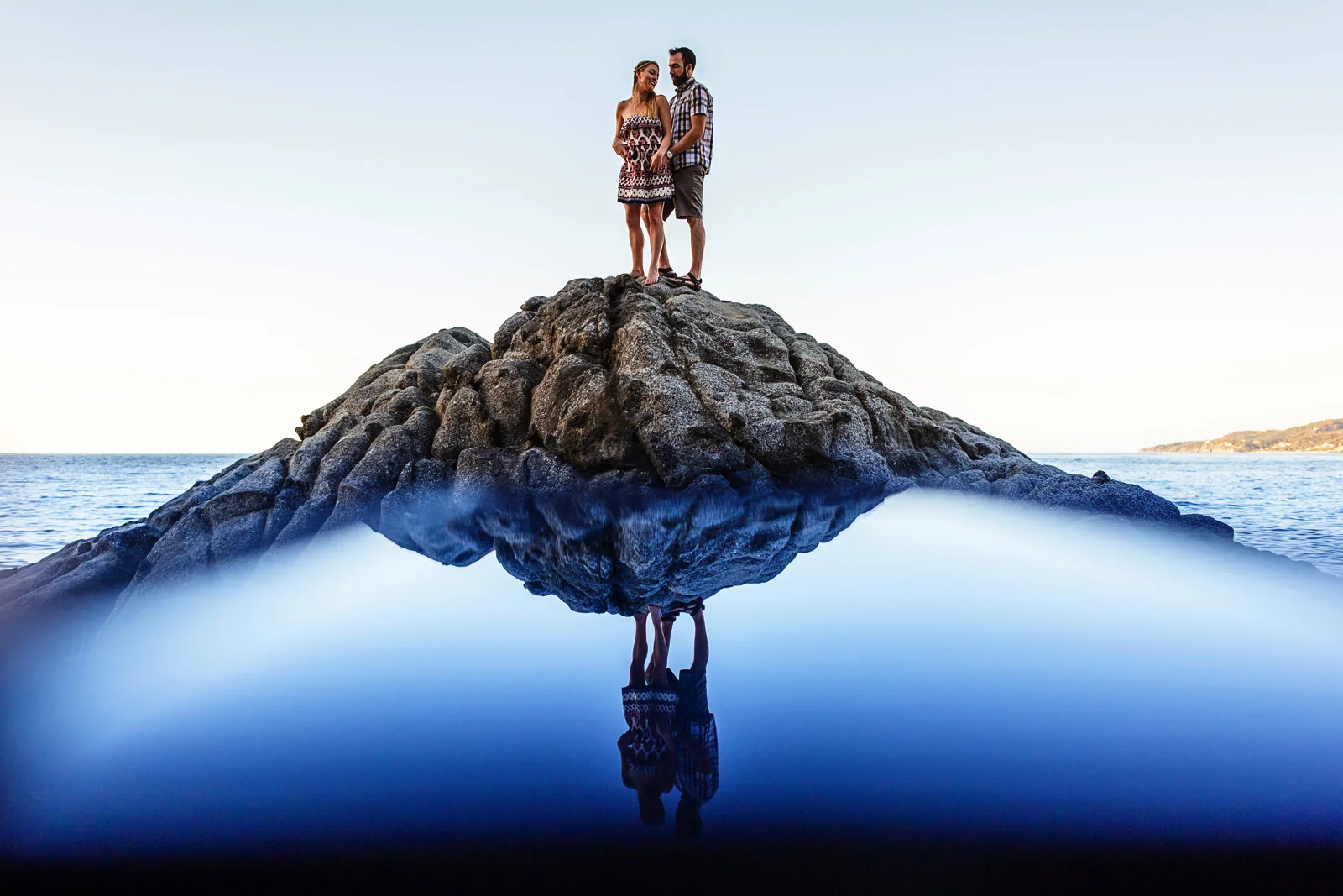 Married couple on the top of a tall rock near the pacific ocean at Playa Los Muertos, in Sayulita.