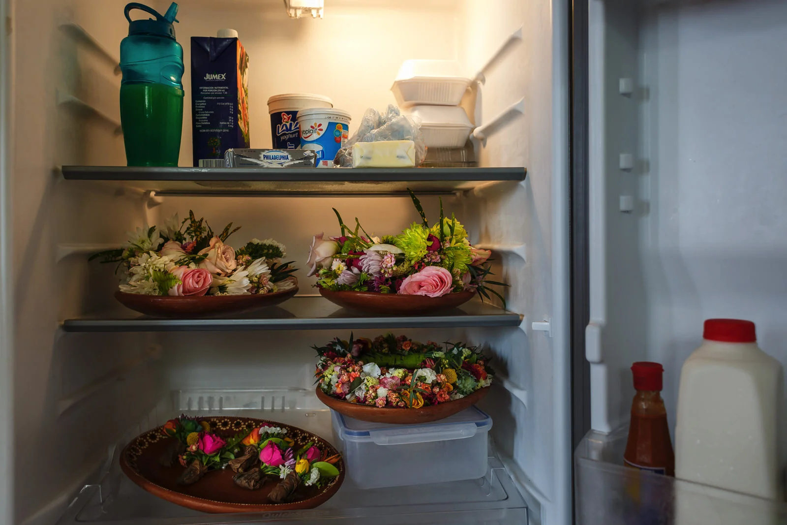 Bouquet, boutonnieres and other flowers stored in the fridge of the suite next to milk, juice and other groceries.
