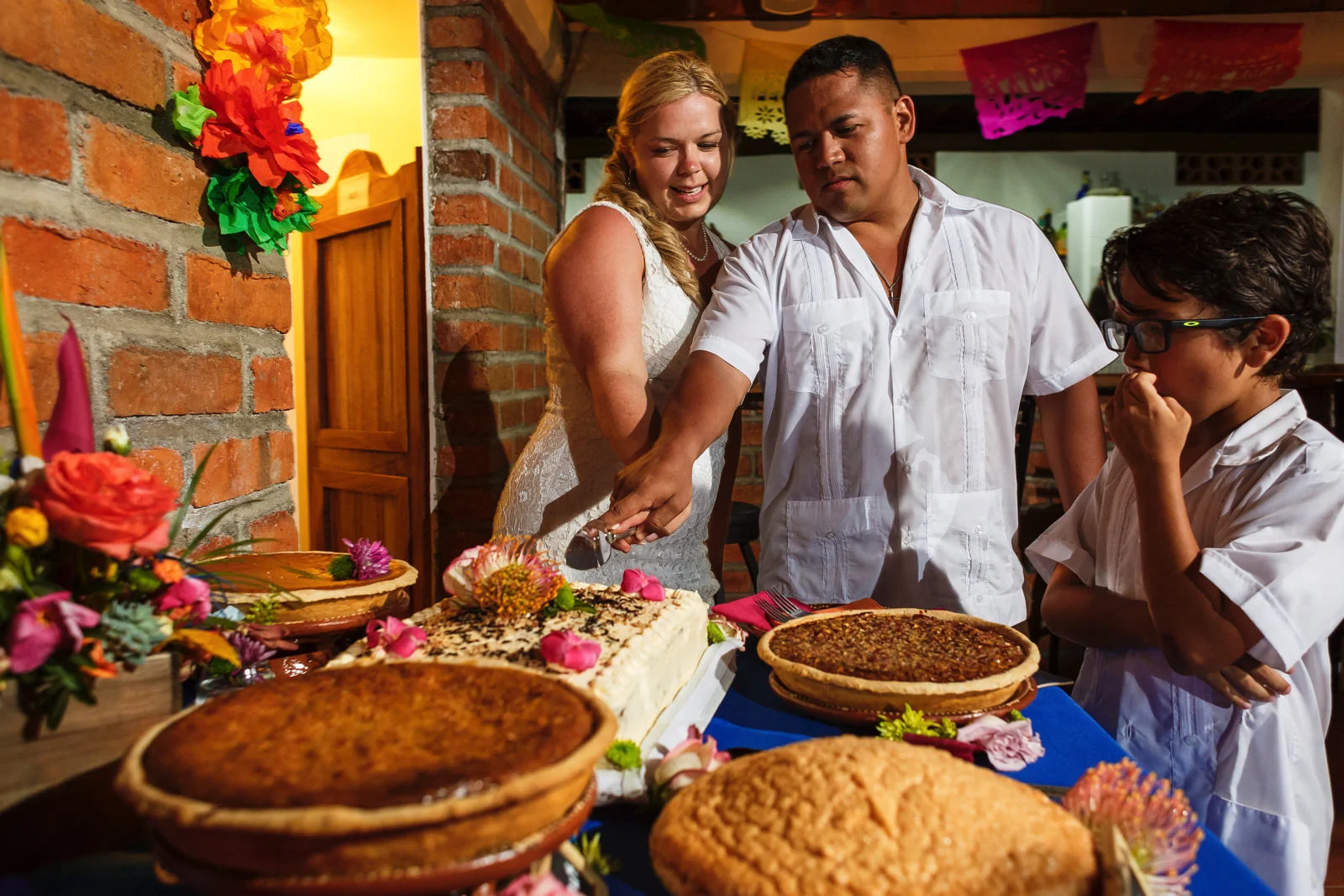 Bride and groom cutting the cake among all the famous and delicious pies from Yelapa, the little guy keeps and eye on all the sugar goodies.