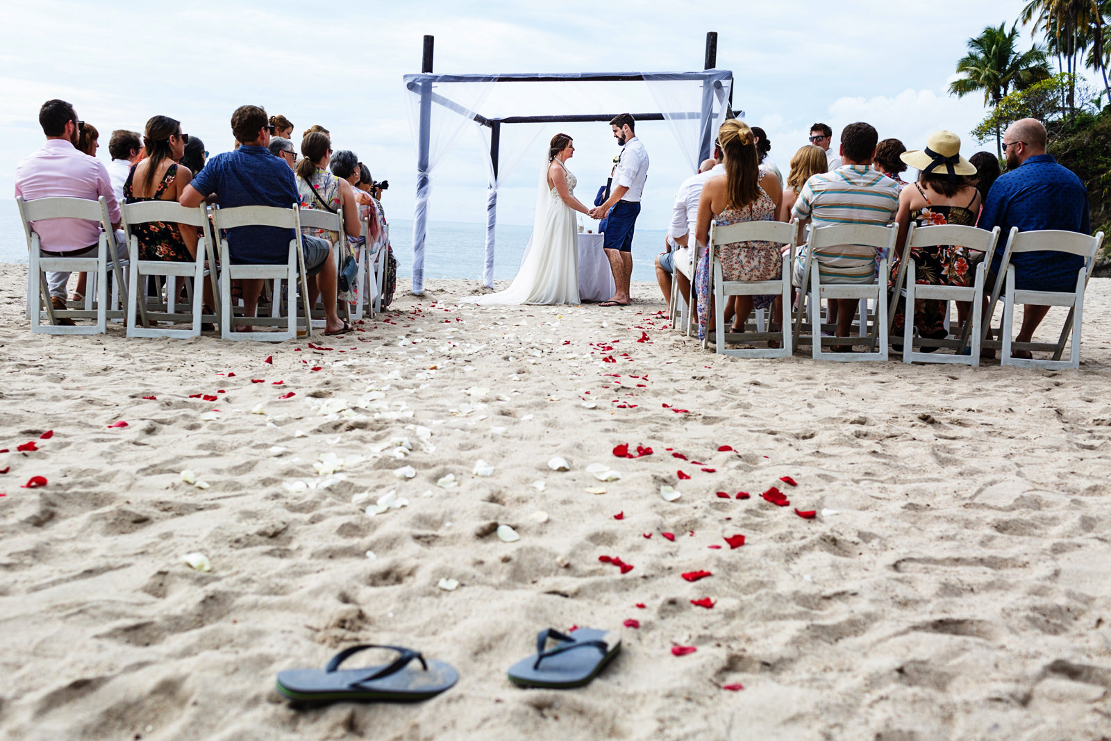 The bride left her flip-flops at the beginning of the aisle for the beach wedding ceremony.