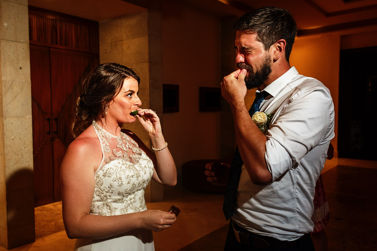 Groom and bride chewing on a slice of lime after having a tequila shot.