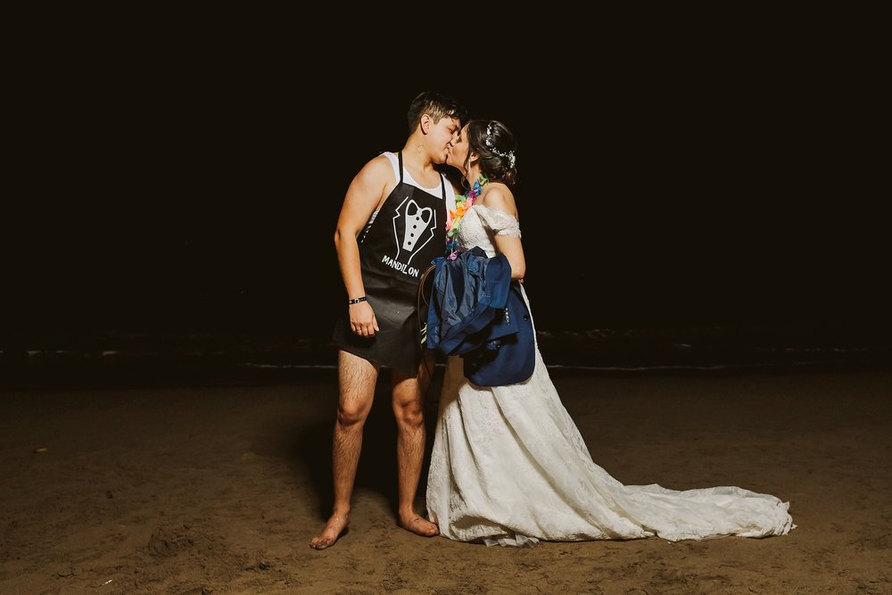 Bride and wet-by-the-ocean groom kiss at the end of the night