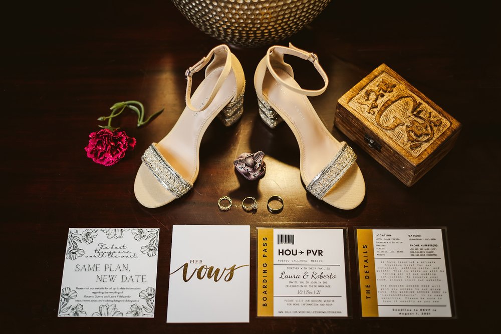 Bride’s shoes, wedding rings and invitations next to a lamp