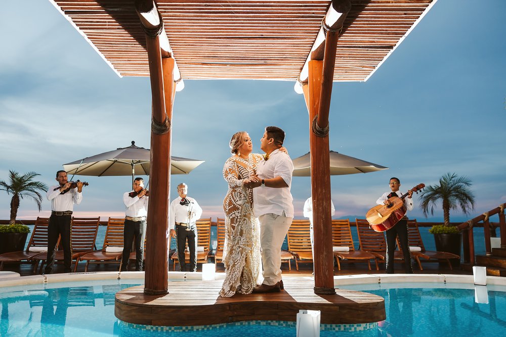 Bride and groom dance to the mariachi band on a deck at Playa Fiesta’s pool