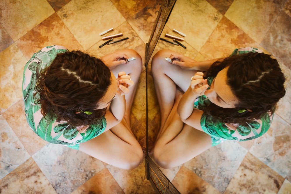 Bride doing her makeup sitting on the floor in front of a mirror