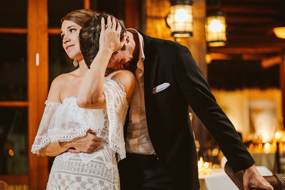 Groom leans into his bride’s shoulder on an intimate moment at their wedding reception