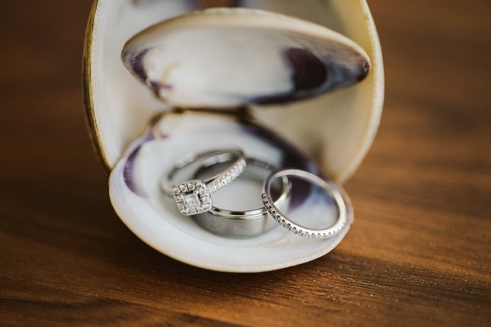 Detail shot of the wedding bands and engagement ring placed on sea shells