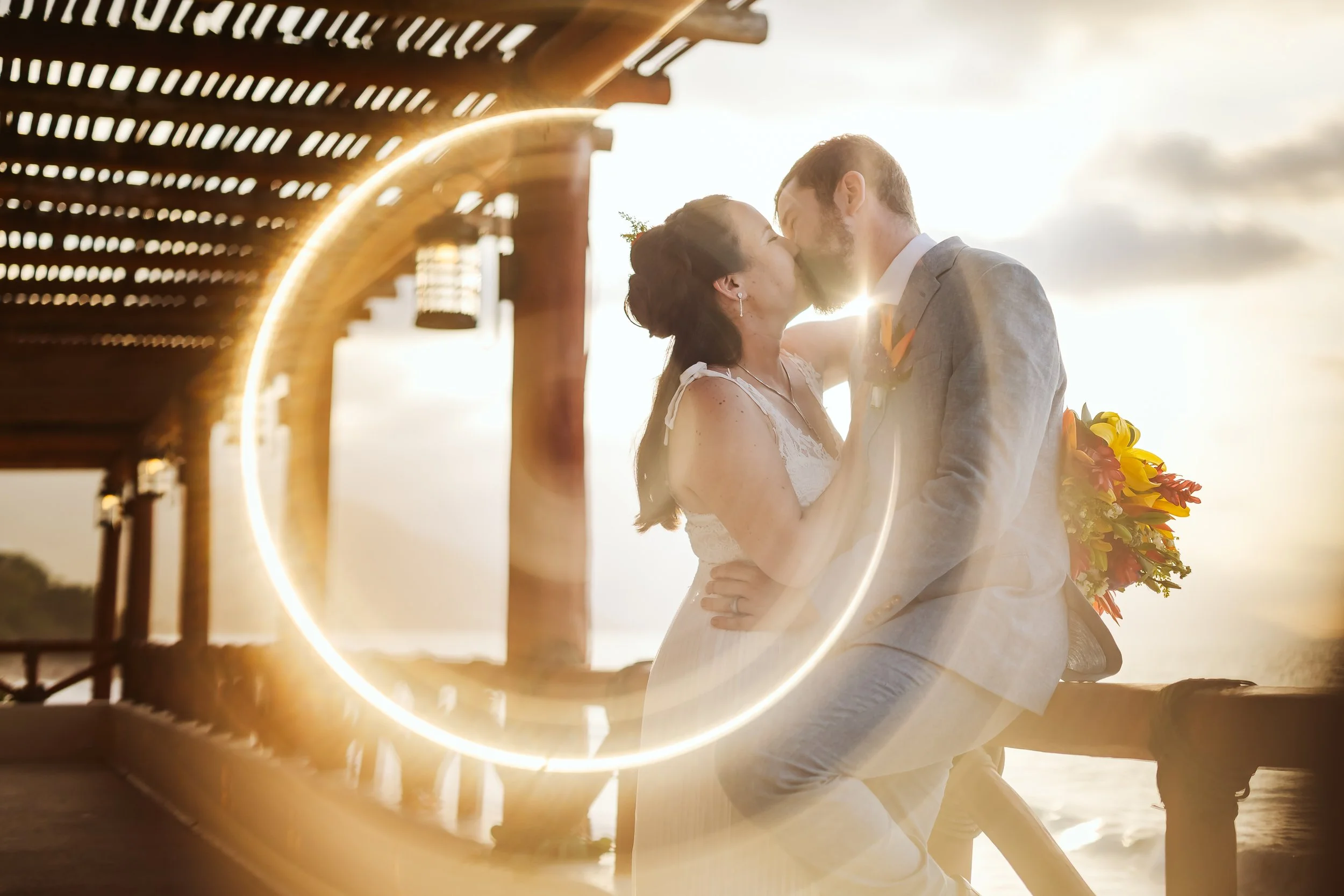 Couple bride and groom kissing at Hotel PLaya Fiesta's terrace at sunset