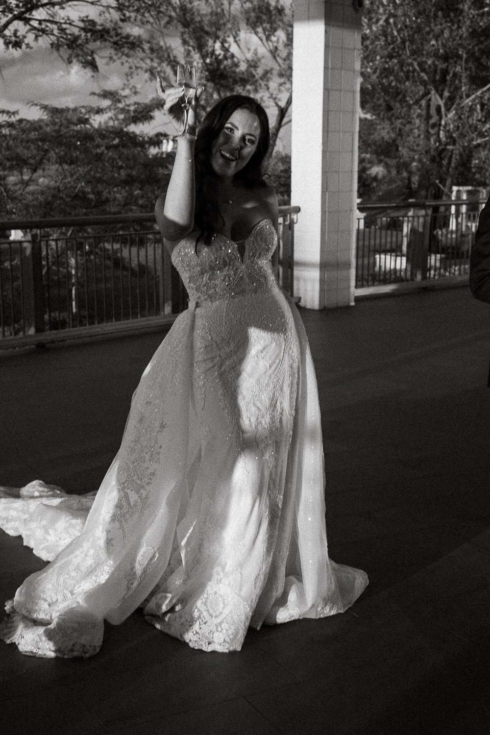 A bride in a wedding dress holding a glass of champagne at night on an outdoor balcony, captured by Montreal wedding photographer.