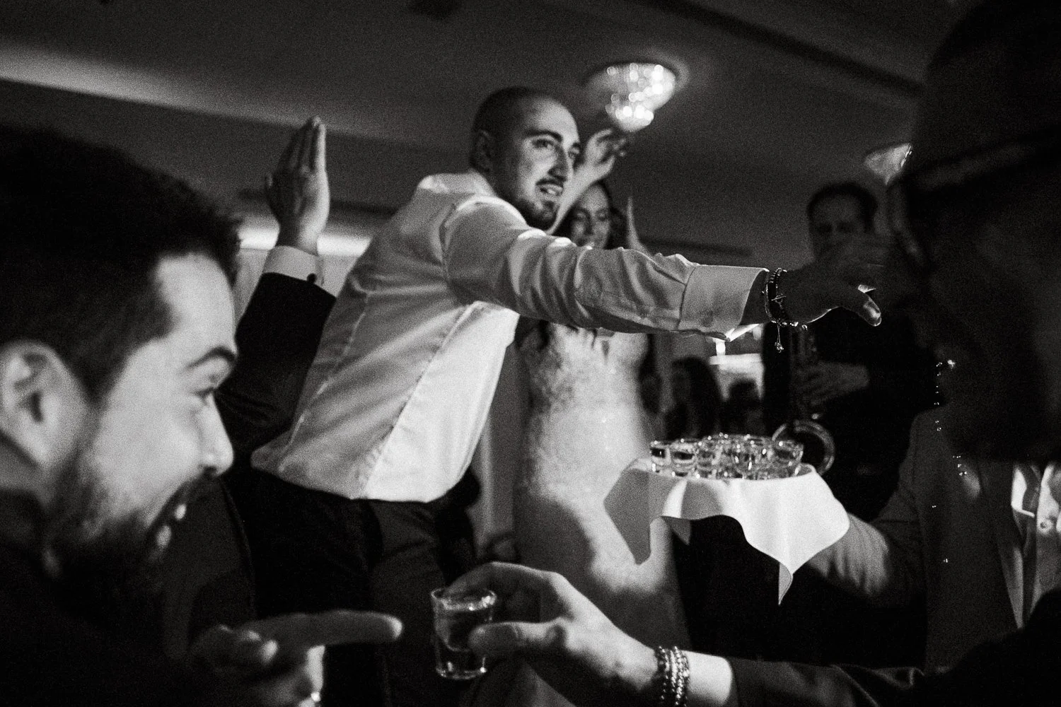 People celebrating at a wedding reception, with one person pouring drinks onto a tray while others are enjoying the event.