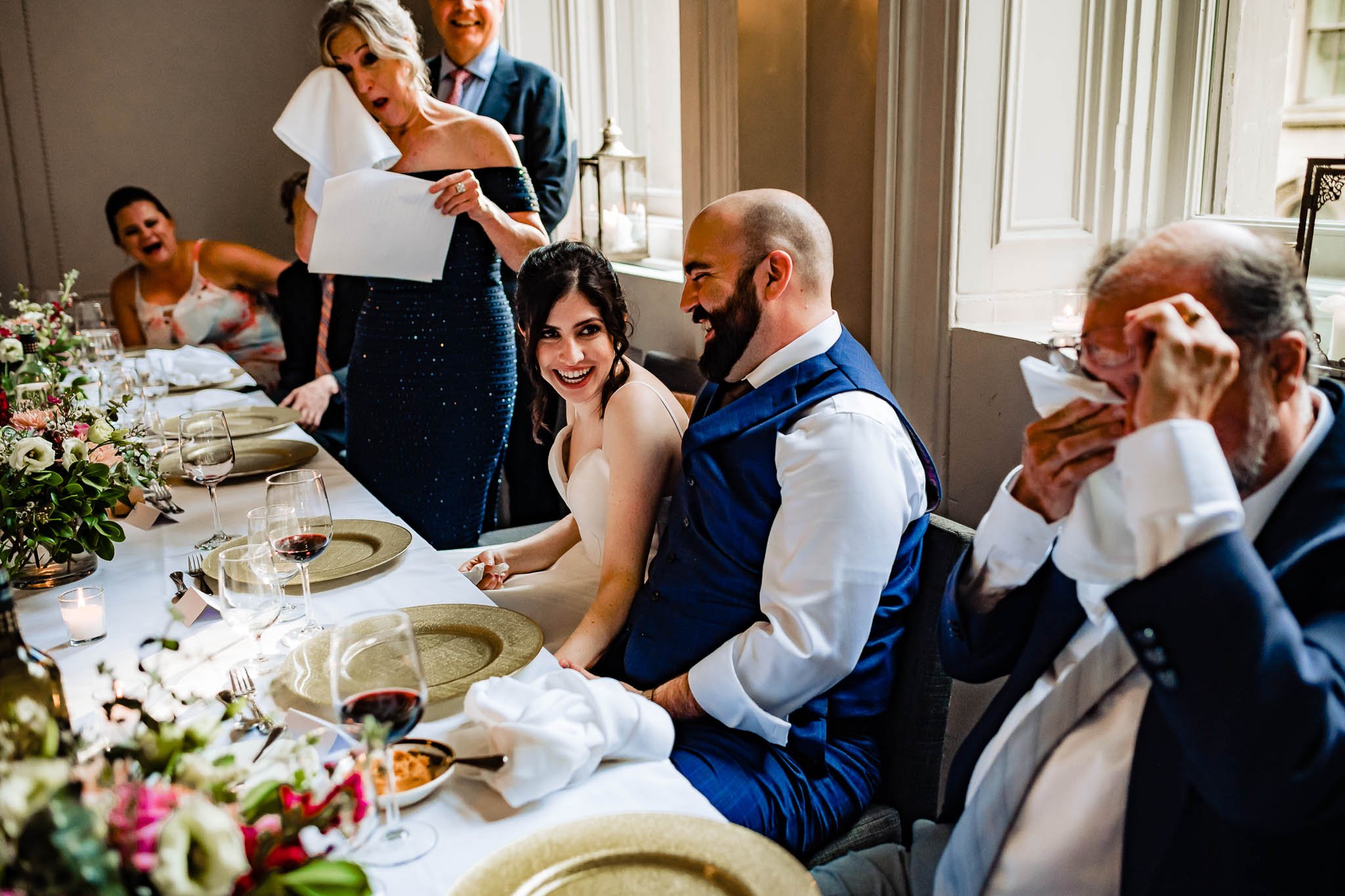 Bride laughing at dinner table with parents wiping tears at The Halifax Club