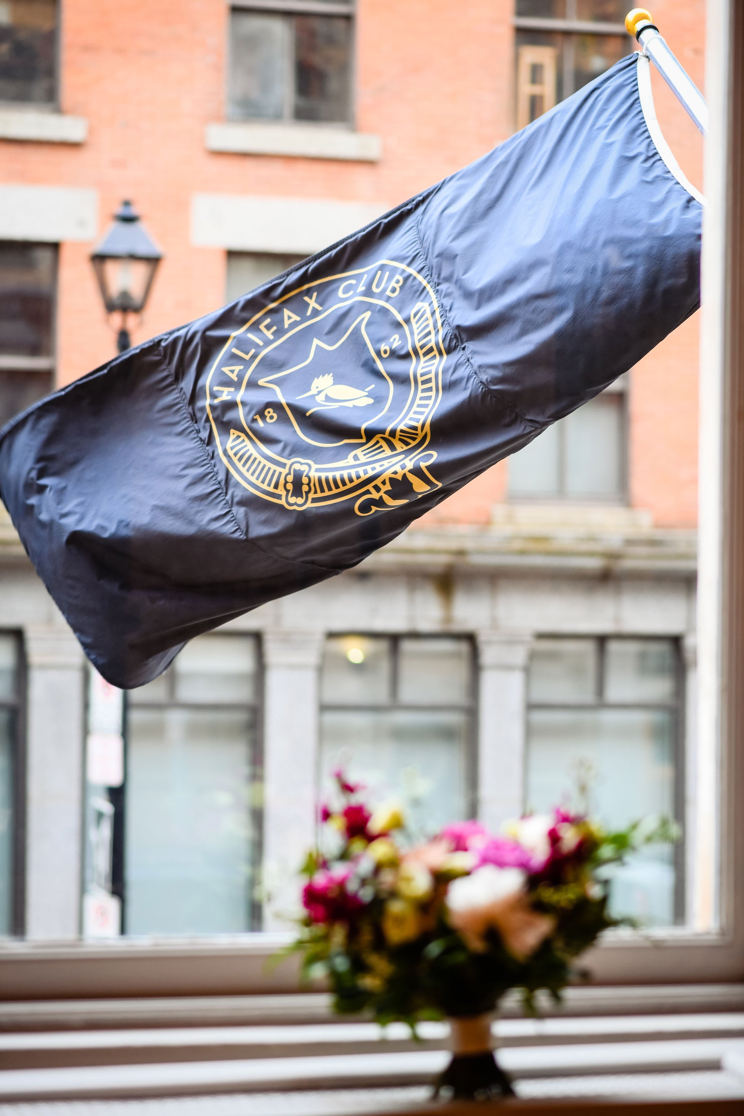 the halifax club flag waving in the wind with boquet blurred inside window