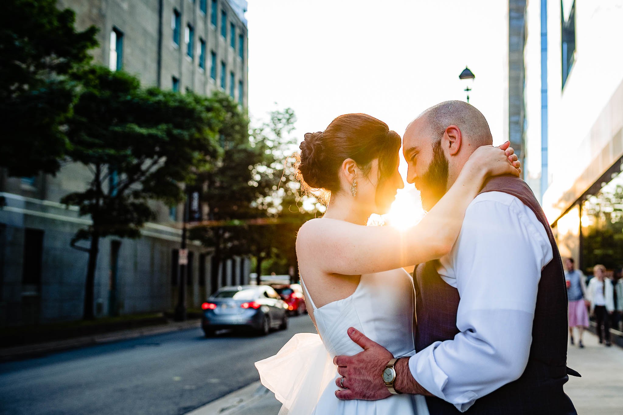 bride and groom embrace head to head with sun beaming through middle of them