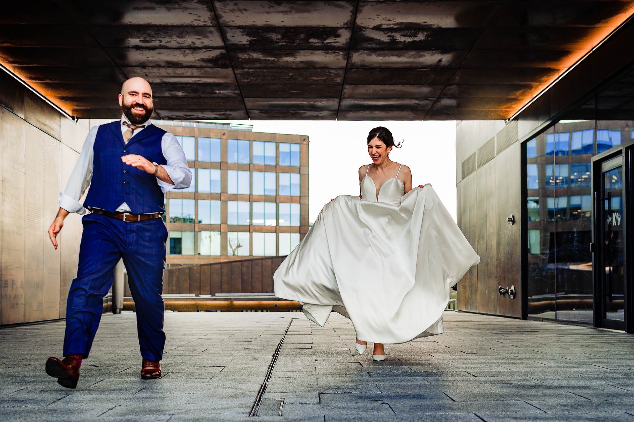 bride and groom running through muir waterfront walkway