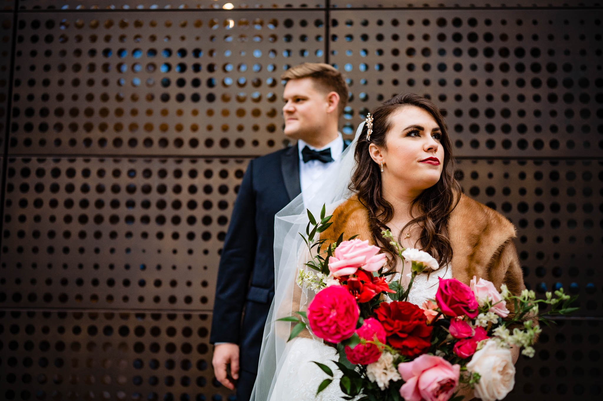 serious pose of bride and groom in front of artistic wall at muir hotel