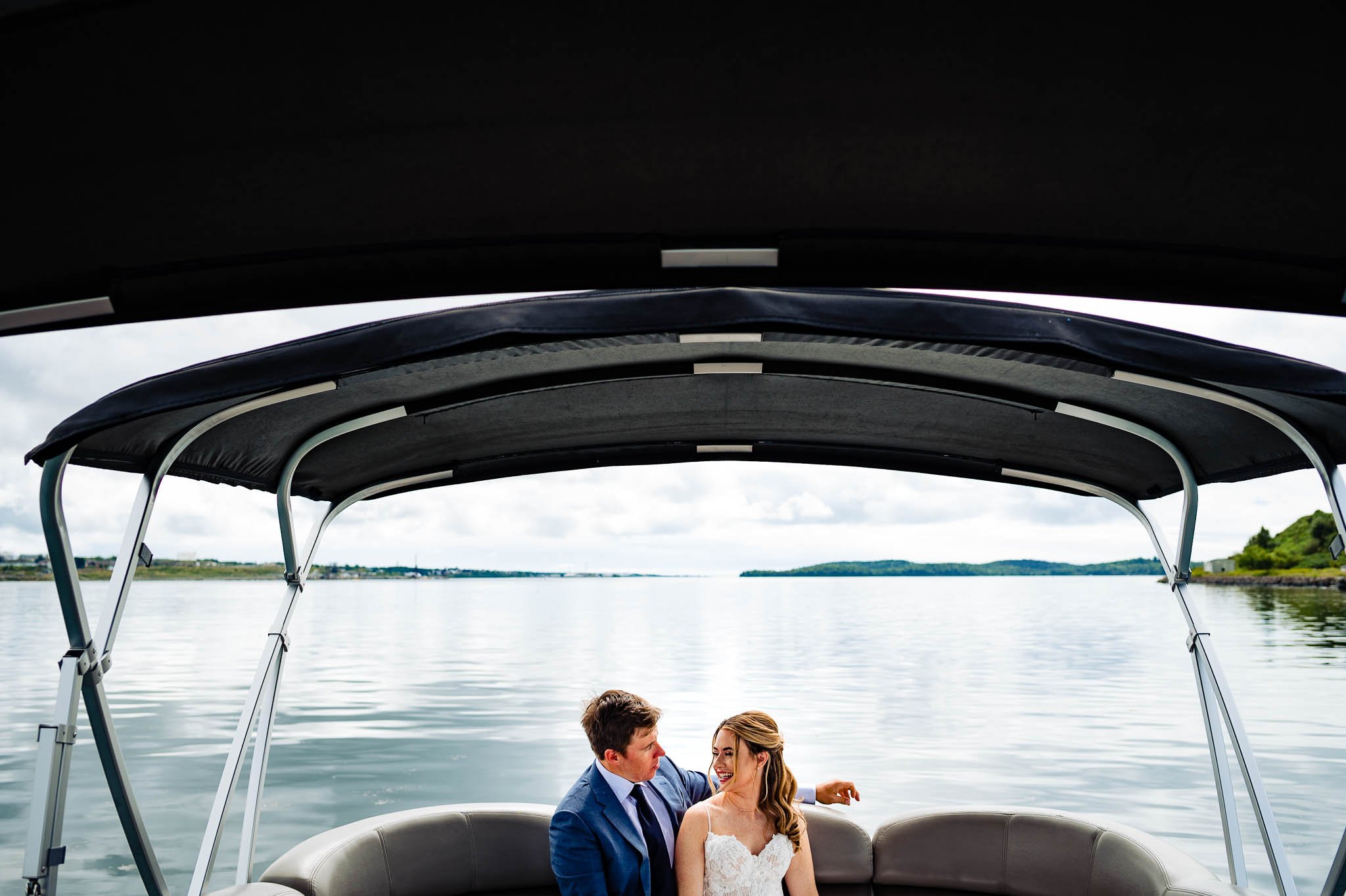 bride and groom sitting in boat on their way to take photos at georges island