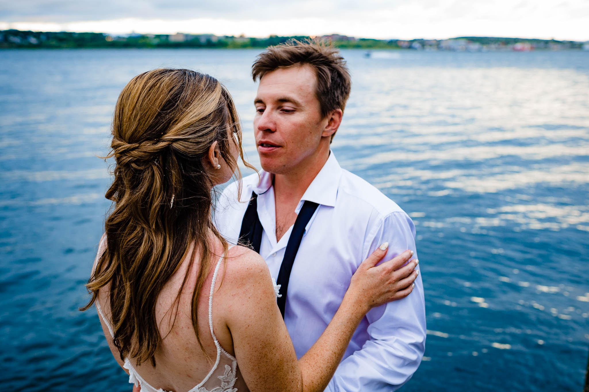 groom looking deeply into brides eyes with water behind them